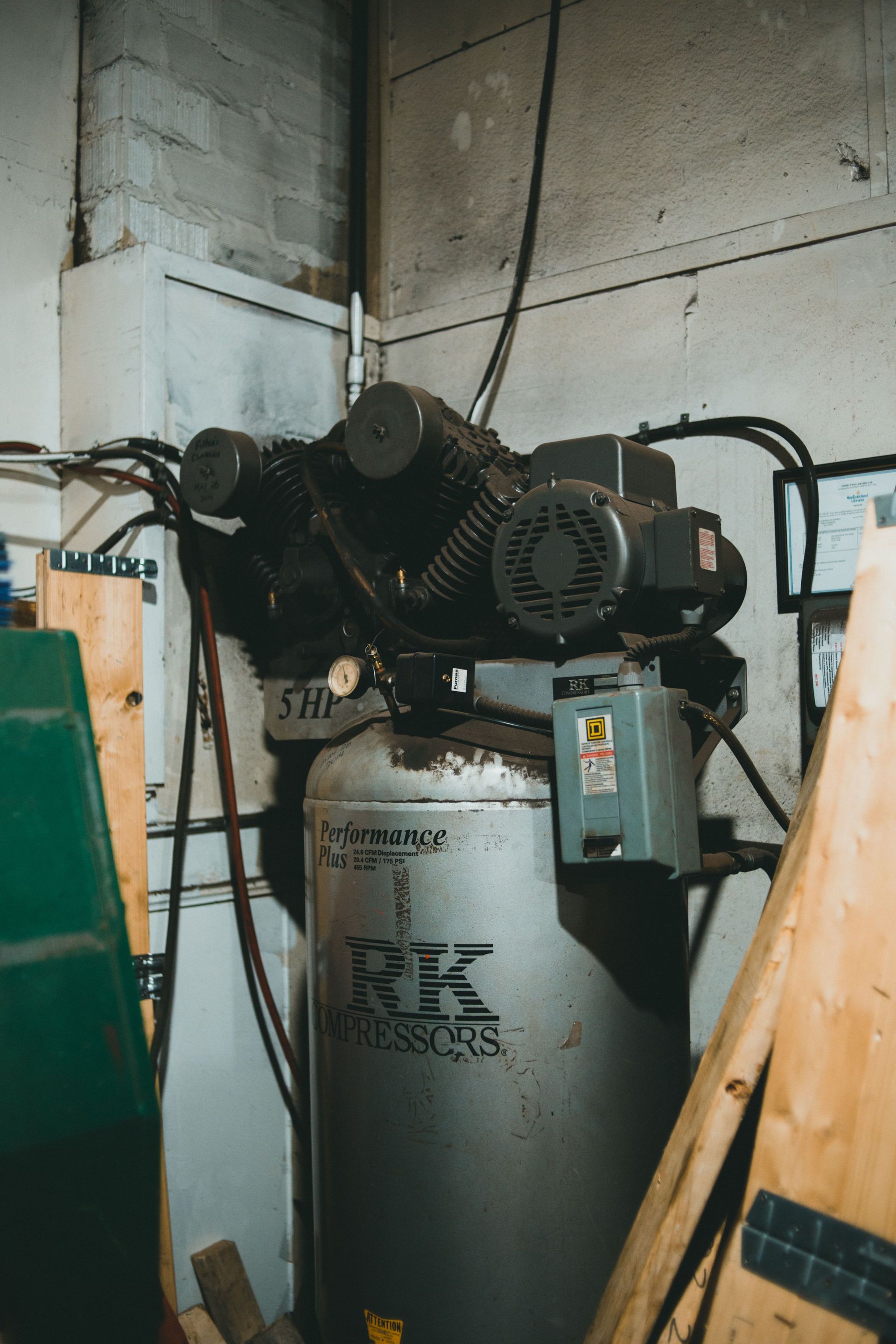 Close-up of a large industrial air compressor in a workshop, showcasing machinery and tools.